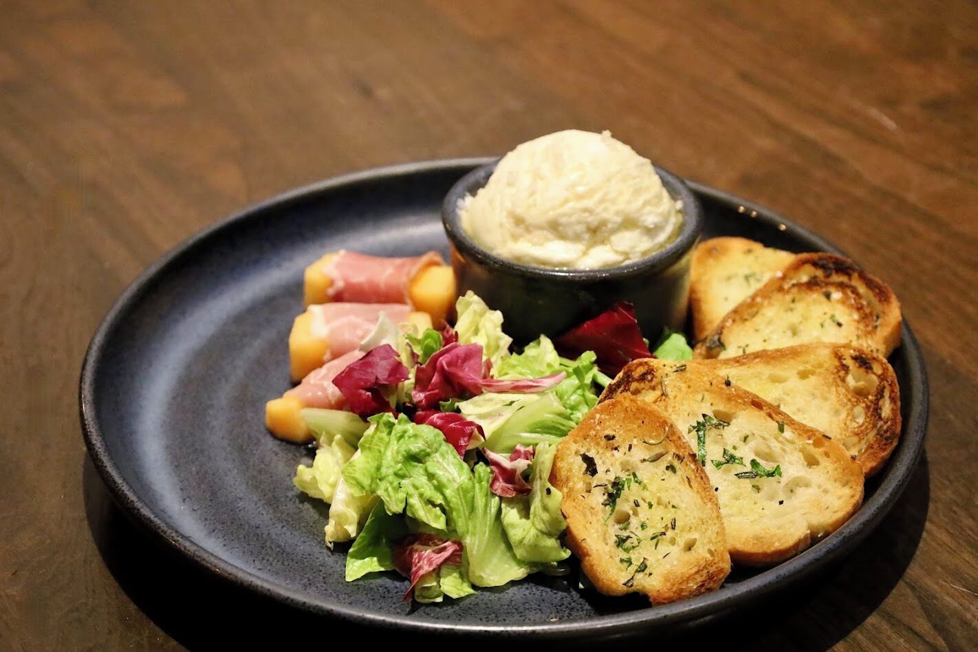 Un plato con pan tostado, una ensalada y un bol de salsa.