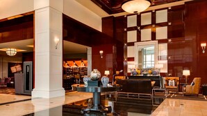 A spacious lobby with a grand chandelier, a reception desk, and a seating area with a coffee table. - Sheraton Overland Park Hotel at the Convention Center (Overland Park)