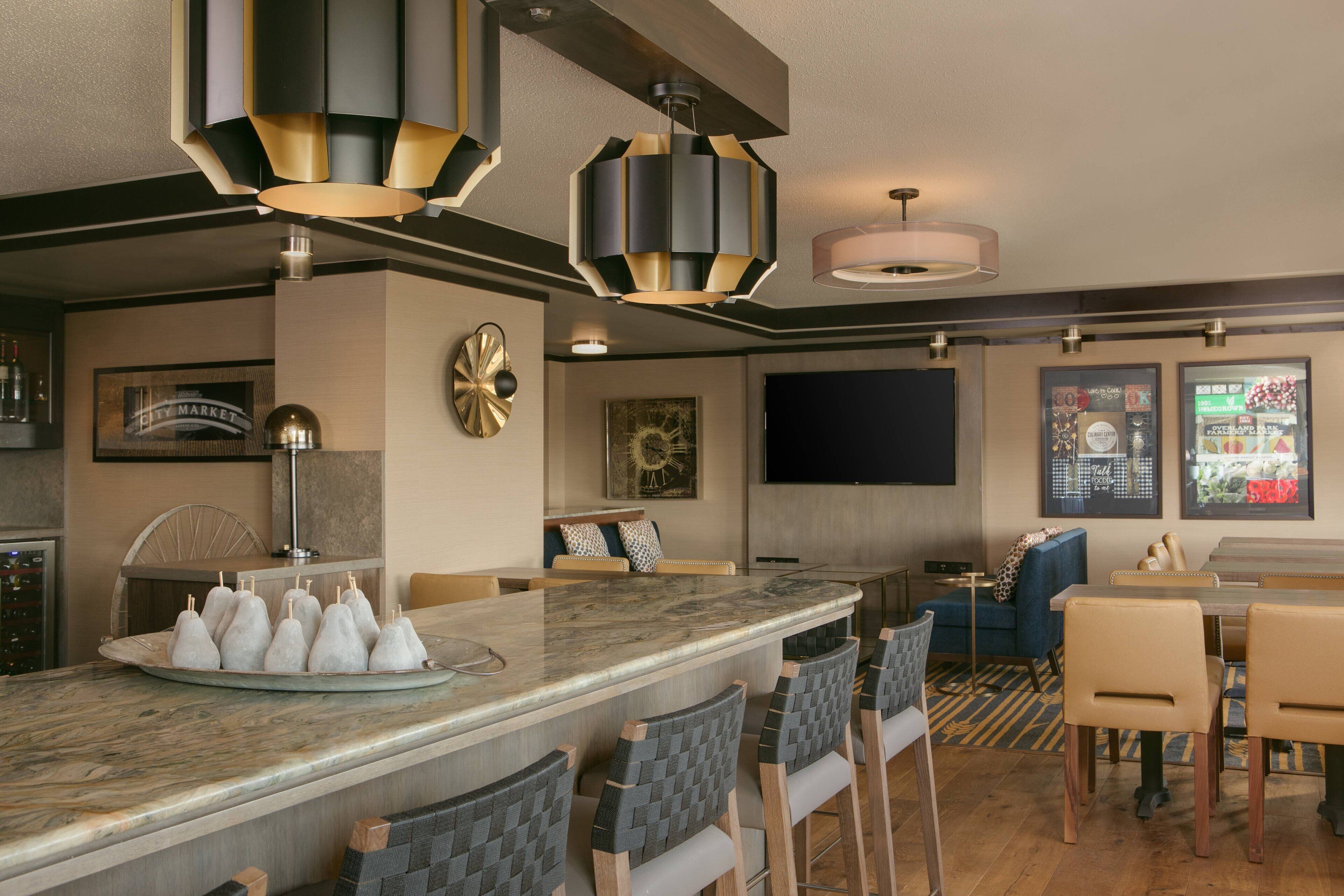 A modern kitchen with a marble island, bar stools, and pendant lighting.