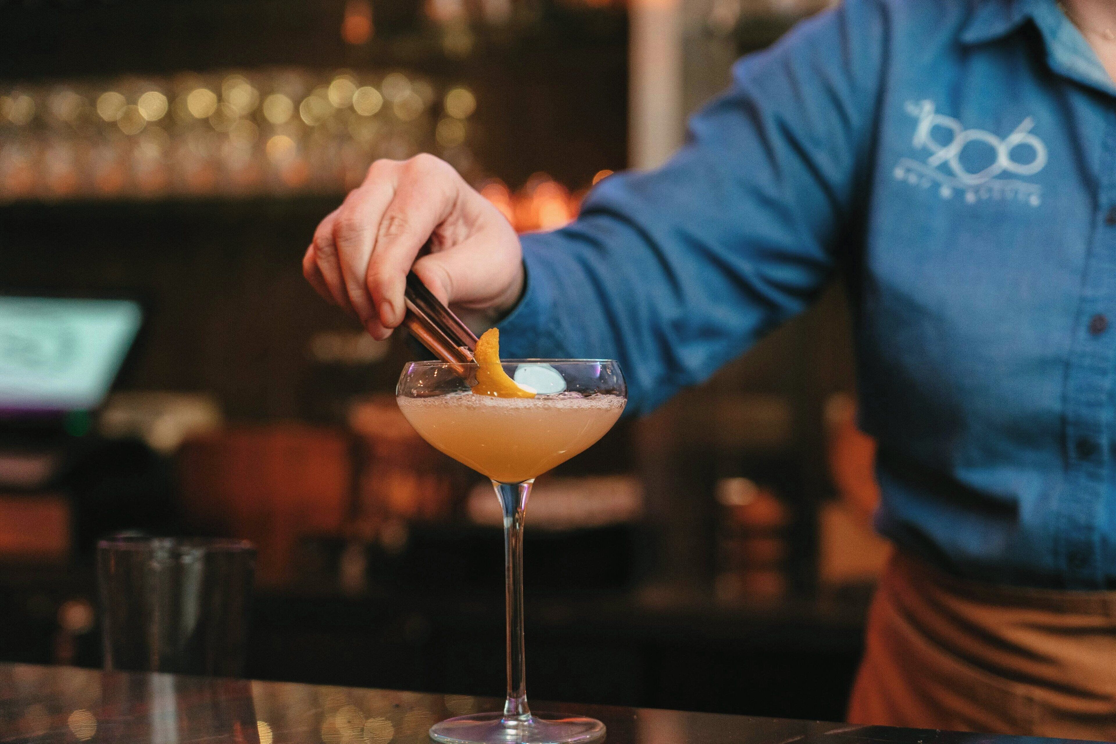 A bartender preparing a cocktail in a bar setting.