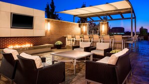An outdoor patio with wicker furniture, a fire feature, and a covered seating area. - Sheraton Overland Park Hotel at the Convention Center (Overland Park)