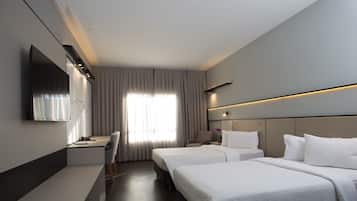Habitación de hotel con dos camas, un escritorio, una silla, un televisor y una ventana con cortinas.