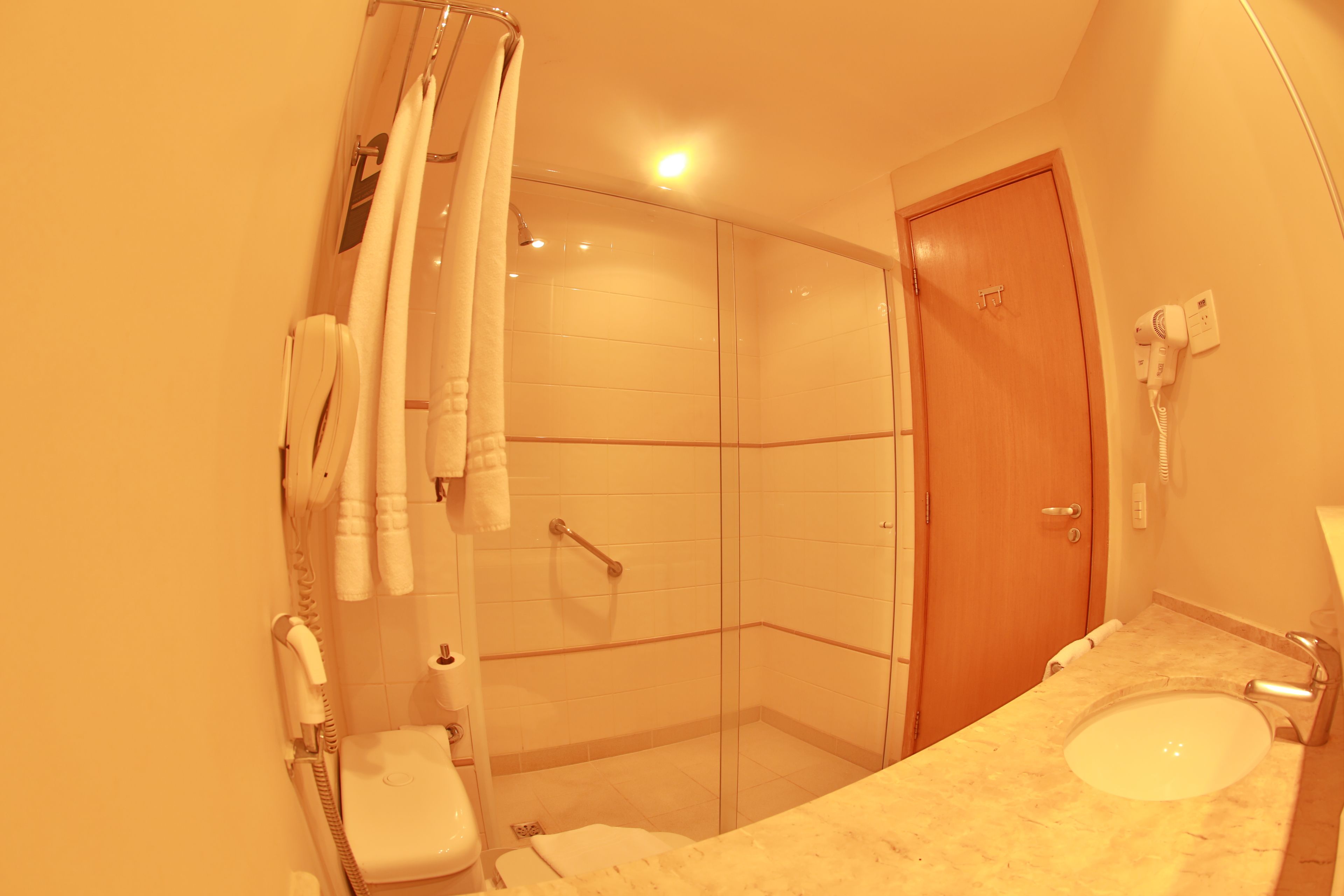 A bathroom with a glass shower enclosure, a toilet, and a sink with a mirror.