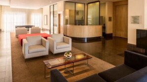 Un moderno vestíbulo de hotel con una recepción, zona de estar y una chimenea.