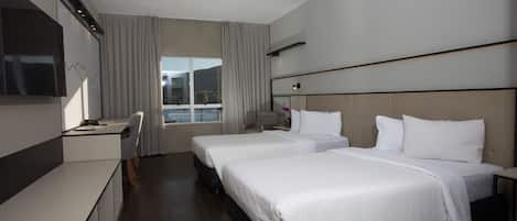 A modern hotel room with two beds, a desk, a TV, and a large window.