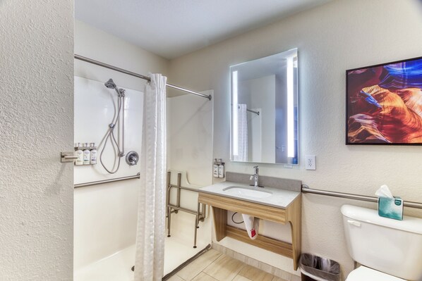Un baño con ducha, lavamanos, inodoro y un espejo grande.