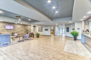 Un hall d’entrée spacieux avec un comptoir d’accueil, un espace salon et un plancher en bois.
