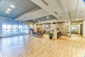 A spacious lobby with a wooden floor, seating area, and a reception desk. - Candlewood Suites New Bern by IHG (New Bern)