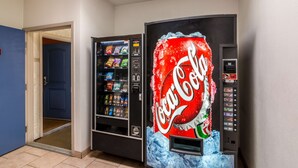 A Coca-Cola vending machine in a hallway with a blue door and a doorbell. - Motel 6 Bell Gardens, CA - Los Angeles (Bell Gardens)