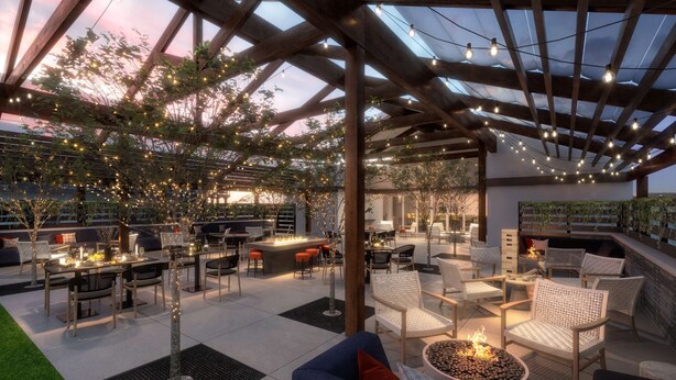 Un patio exterior con pérgolas de madera, luces colgantes y zonas de estar.