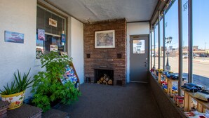 Una habitación con chimenea de ladrillo, una ventana con vista a la calle y una estantería con juguetes.