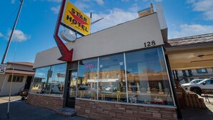 Un Hotel Star con una gran señal de flecha, un letrero visible que dice 'ABIERTO' y fachada de ladrillo.