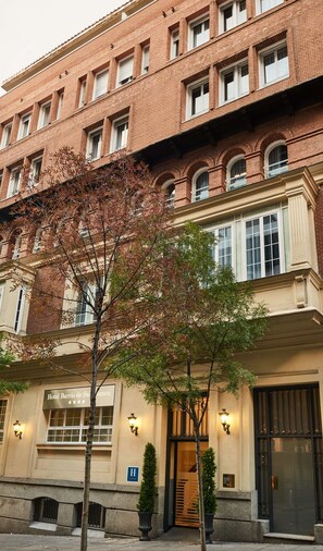 Un hôtel à plusieurs étages, doté d’une façade en briques, de grandes fenêtres et d’une enseigne indiquant qu’il s’agit d’un hôtel.