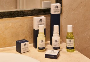 A bathroom counter with toiletries including a hair conditioner, body wash, shampoo, and toilet soap.