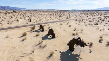 Paisaje desértico con una carretera y estatuas de caballos.