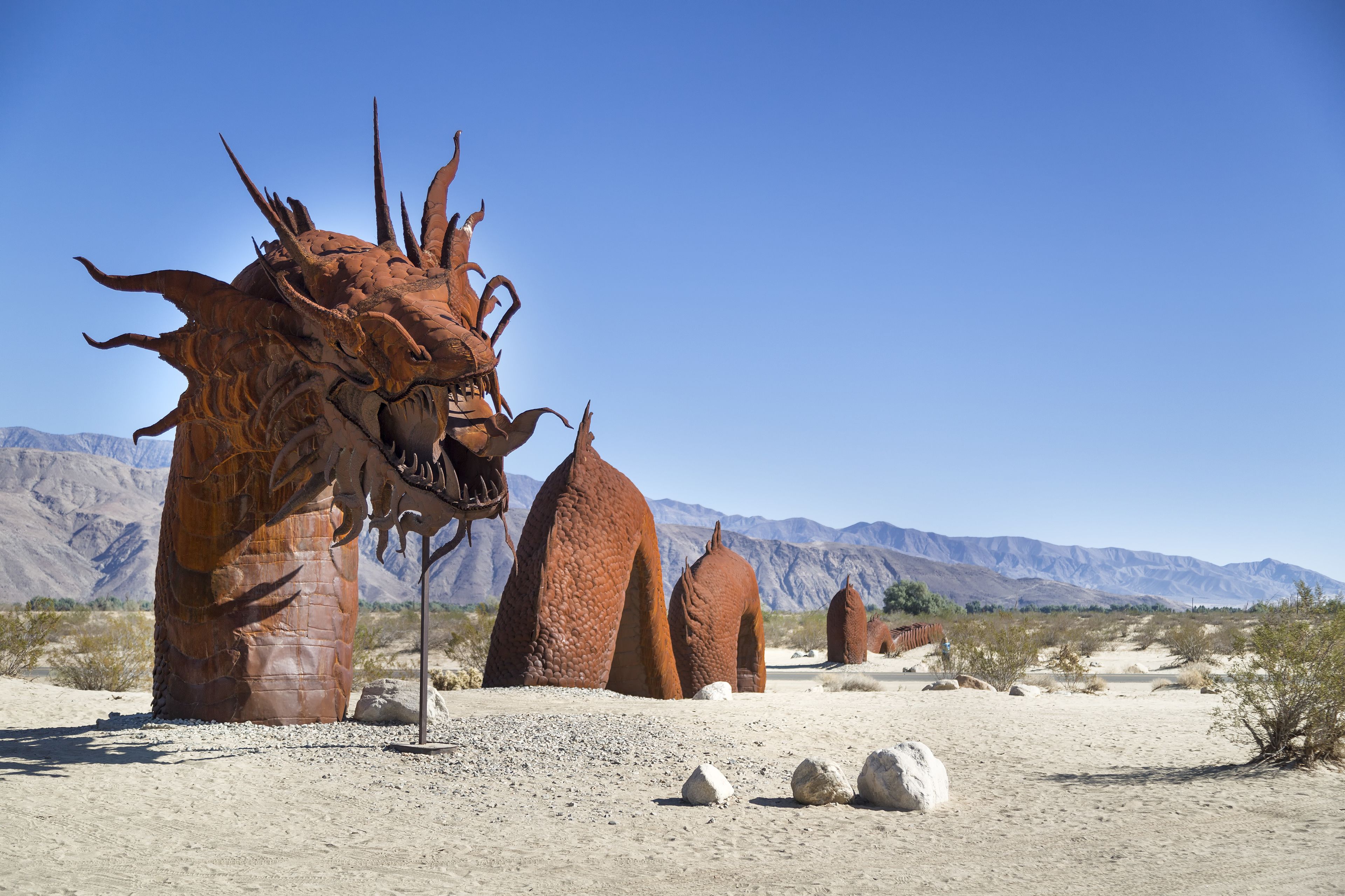 A desert landscape with large, rust-colored rock formations resembling a dragon.