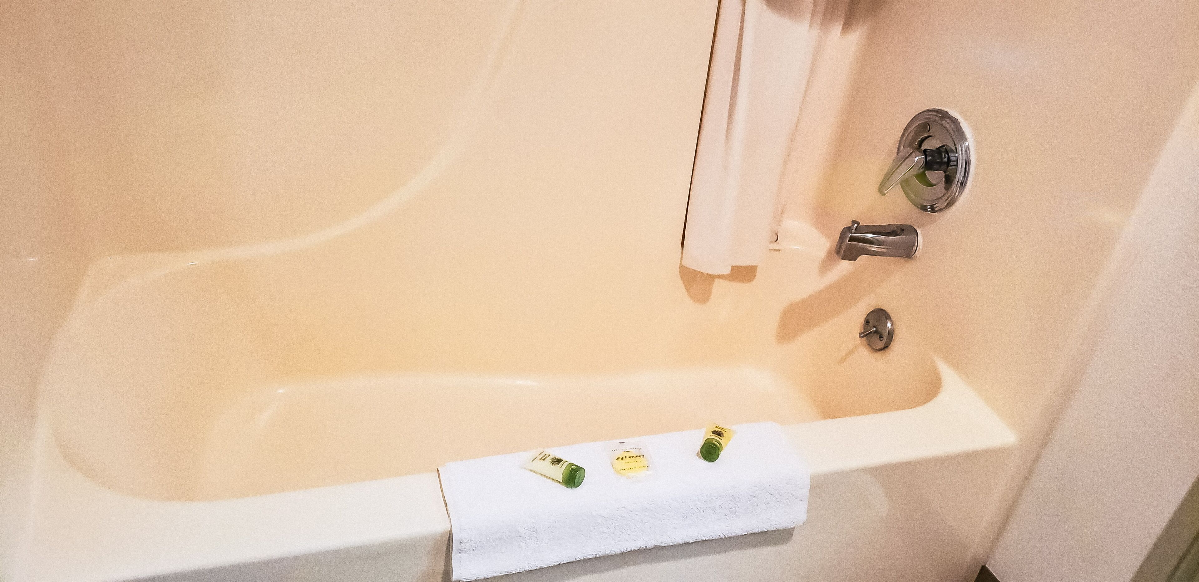 A bathtub with a white towel and two bottles of shampoo.