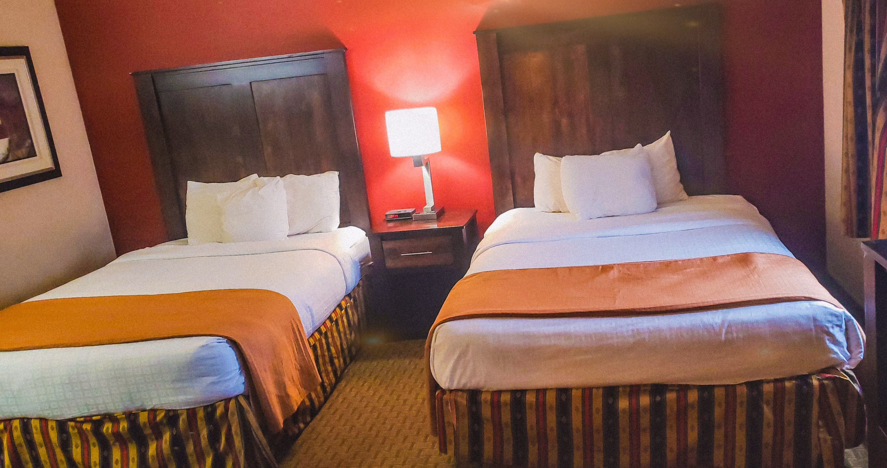 Two single beds with wooden headboards, a nightstand with a lamp, and a striped bed runner.