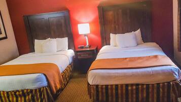 Two single beds with wooden headboards, a nightstand with a lamp, and a striped bed runner.