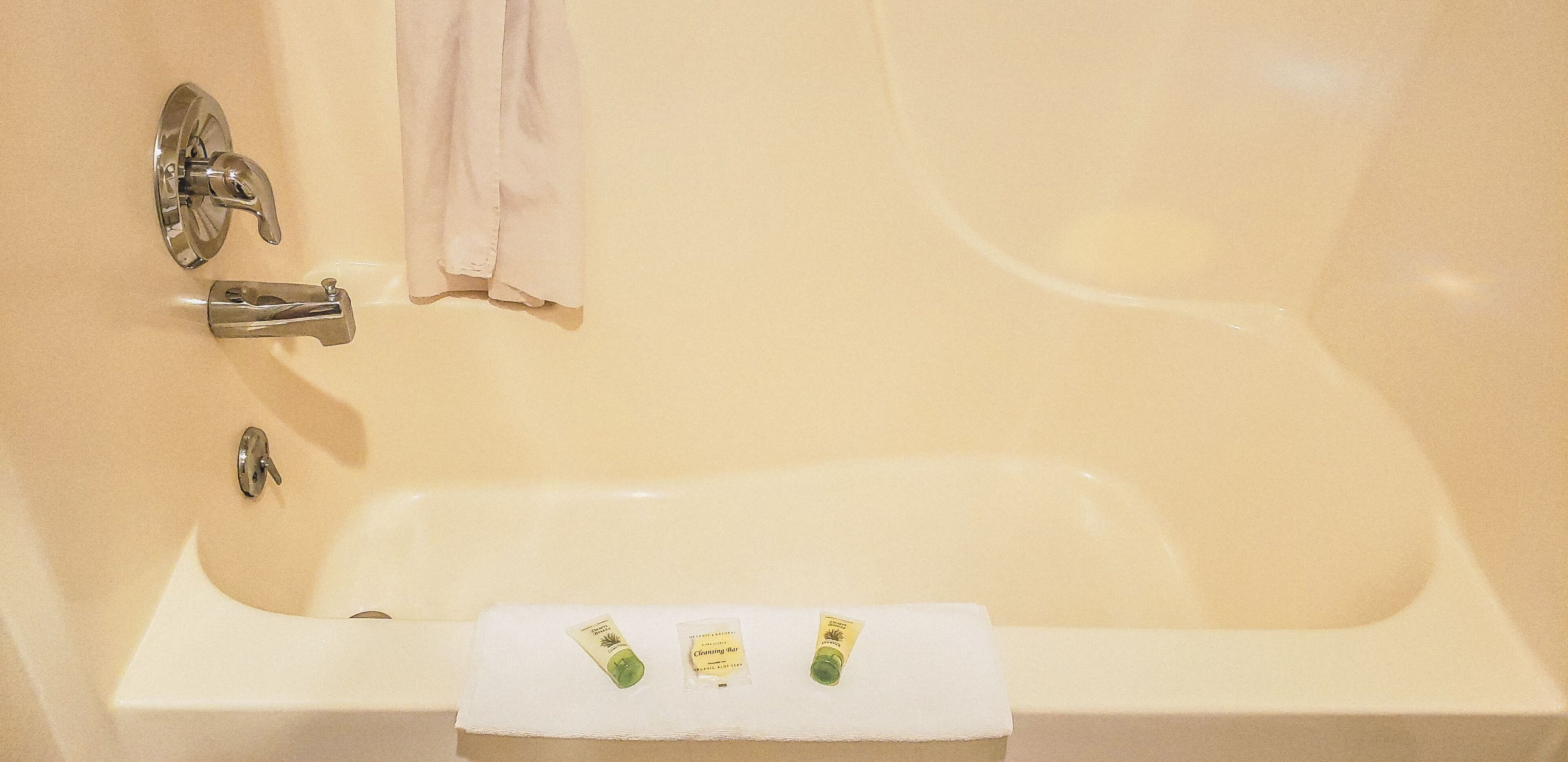 A bathtub with a white towel and two bottles of lotion.