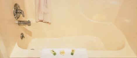 A bathtub with a white towel and two bottles of lotion.