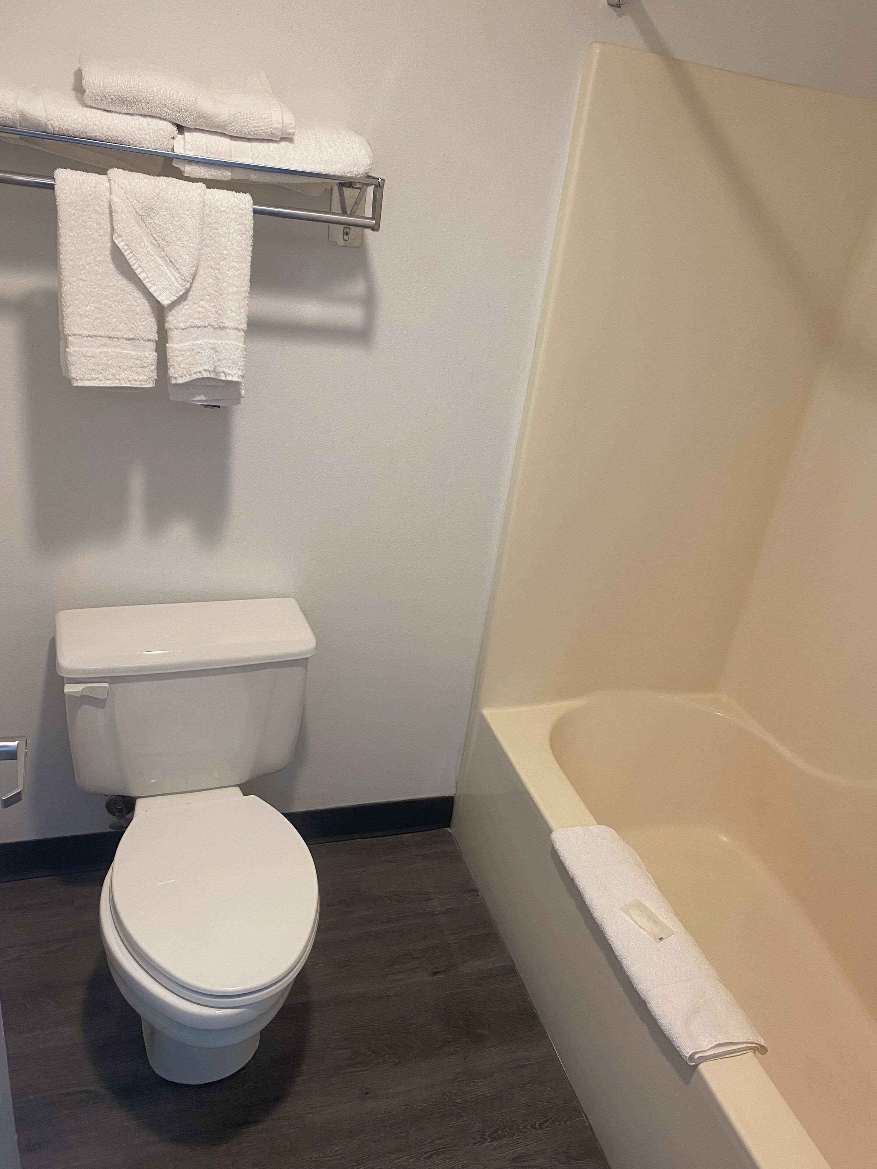 Ein Badezimmer mit Toilette, einer Badewanne und einem Handtuchhalter mit gefalteten Handtüchern.