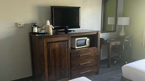 A hotel room with a bed, a wooden dresser with a television, a microwave, and a desk with a chair. - Inn America - Lewiston (Lewiston)