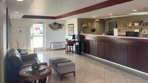 A hotel lobby with a reception desk, seating area, and a large window. - Inn America - Lewiston (Lewiston)