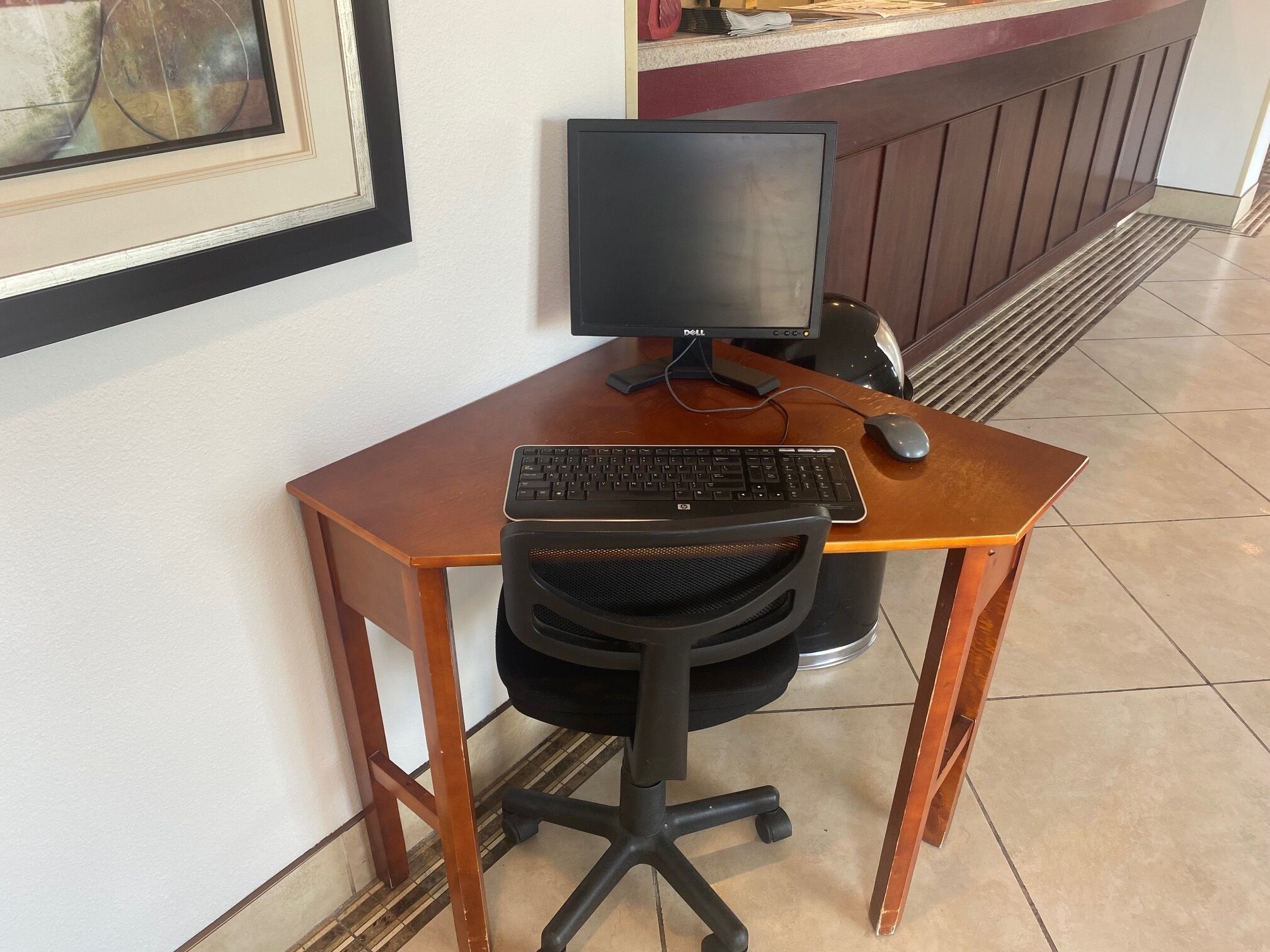 A wooden desk with a computer setup including a monitor, keyboard, and mouse.