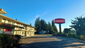 A vacant Snooz Inn motel with a large signboard, surrounded by trees and a parking lot. - Snoozinn (Wilsonville)