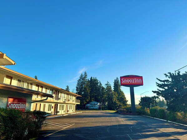 A vacant Snooz Inn motel with a large signboard, surrounded by trees and a parking lot. - Snoozinn (Wilsonville)