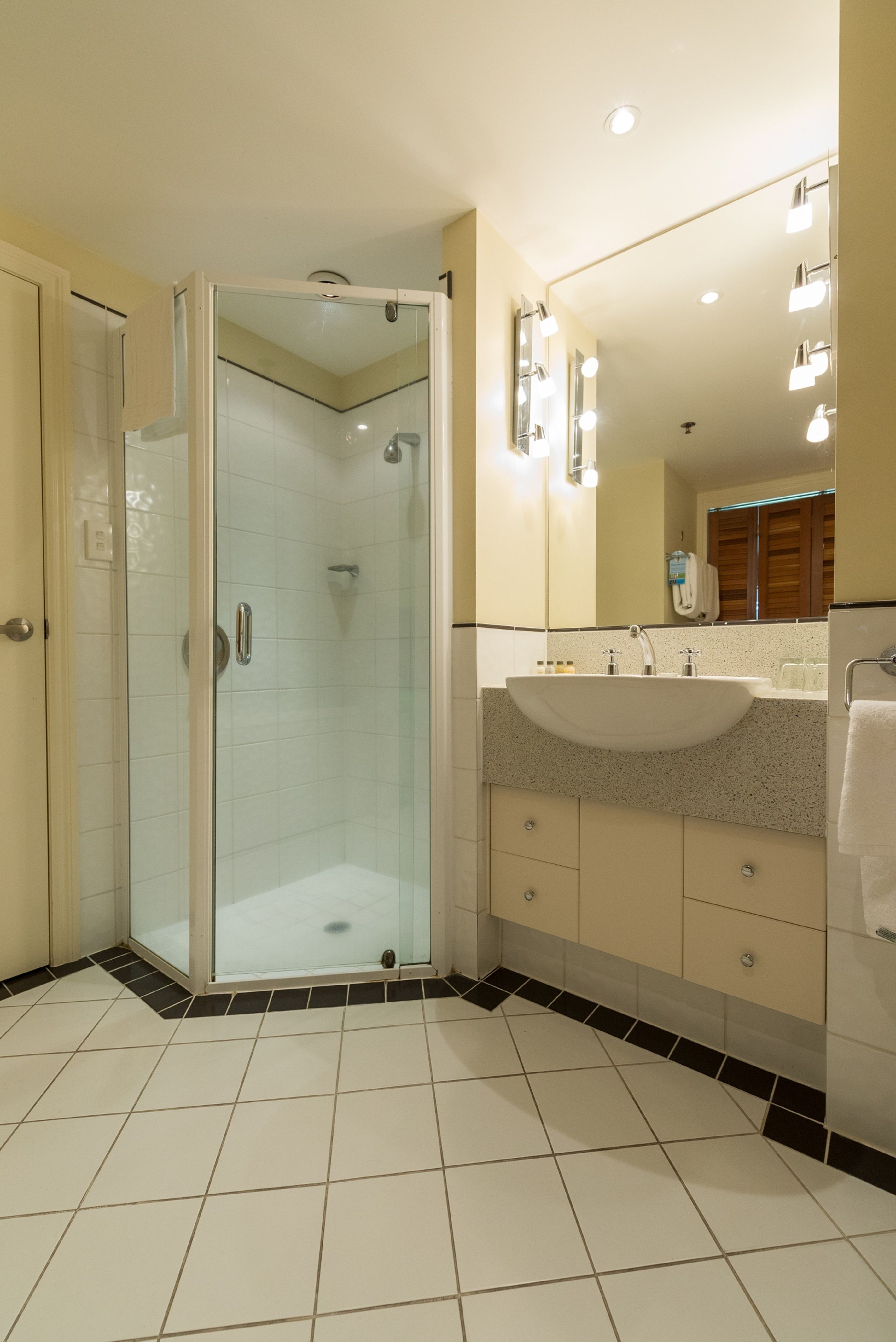 Un baño moderno con ducha envuelta en vidrio, un lavamanos grande y un espejo con iluminación.