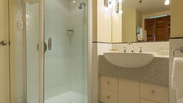 Un baño moderno con ducha envuelta en vidrio, un lavamanos grande y un espejo con iluminación.