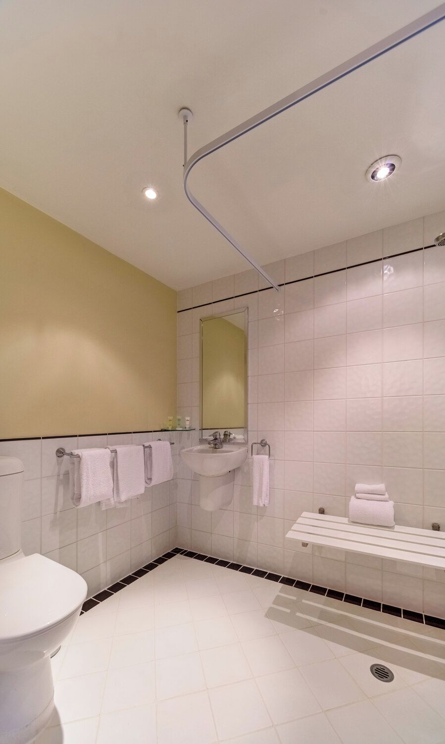 Un baño moderno con inodoro, lavamanos y zona de ducha.