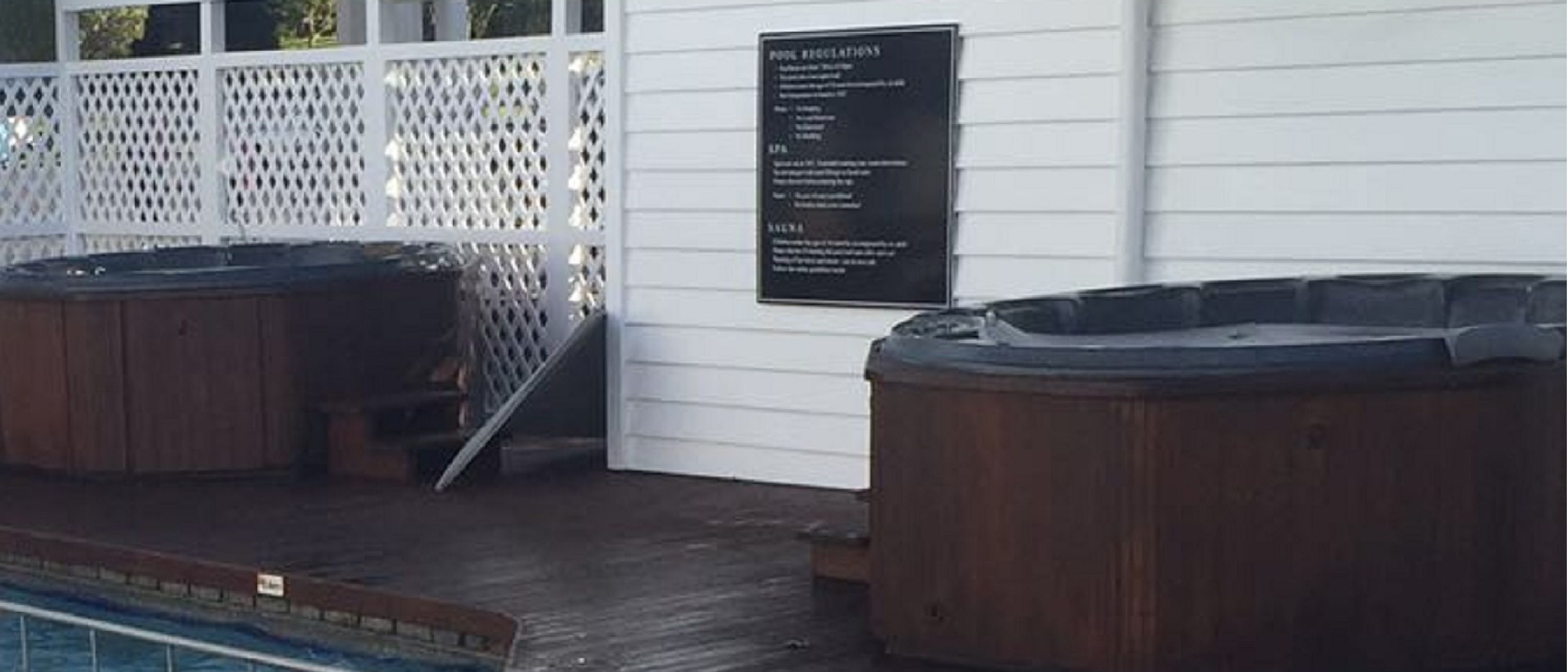 Uma área de piscina com banheiras de hidromassagem e um deck de madeira.