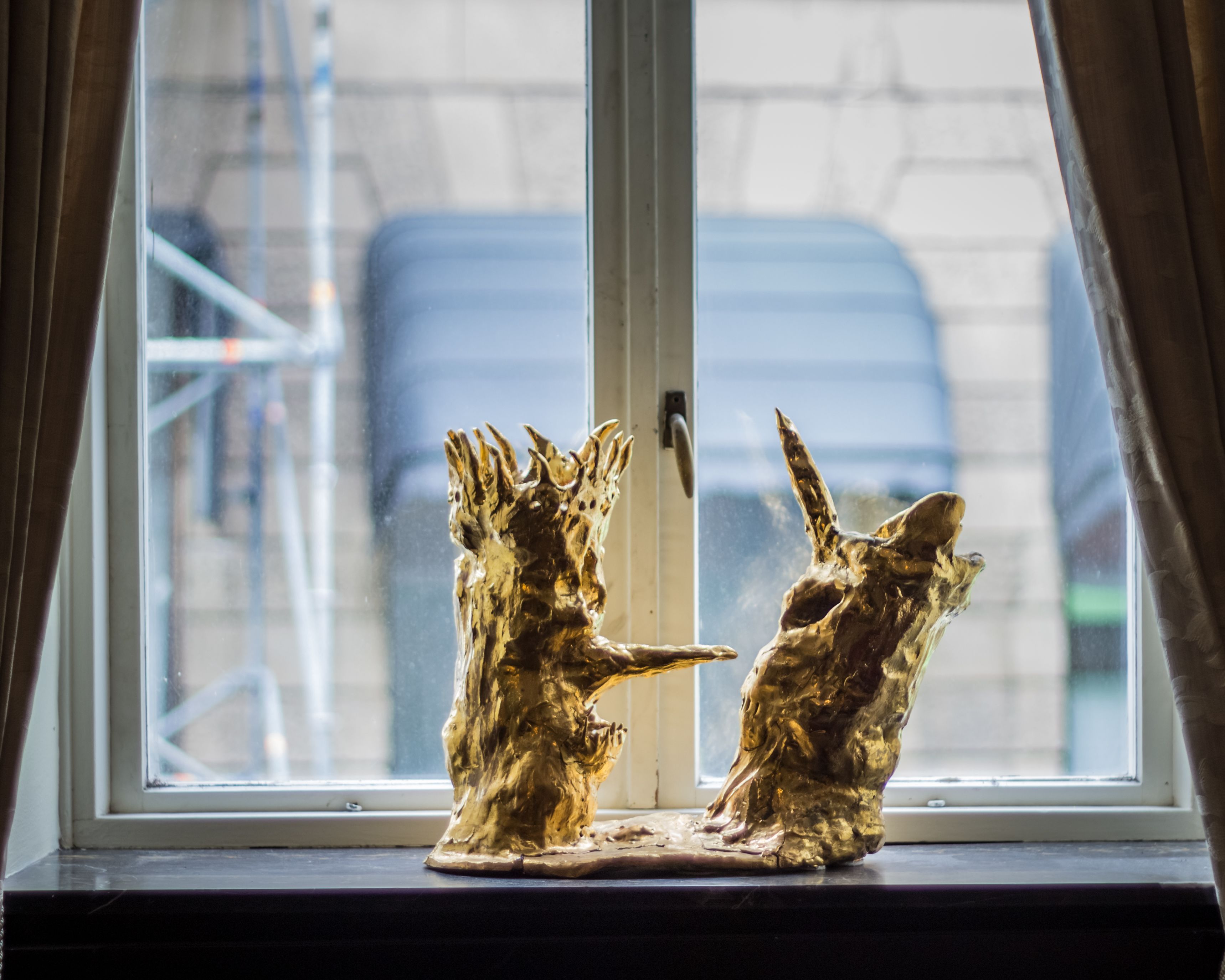 Una ventana con dos estatuas doradas de animales.