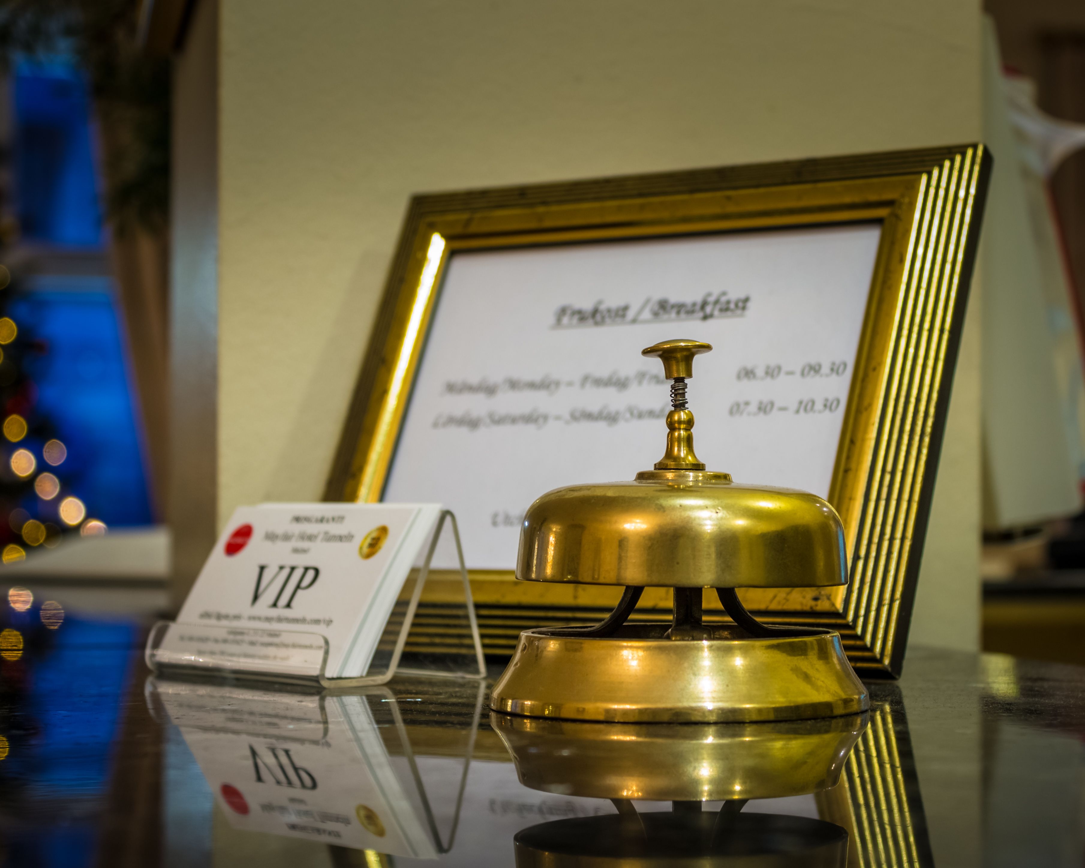 Een bronzen bel met een gouden omlijsting, een VIP-bord en een menukaart op de achtergrond.