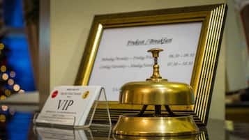 Een bronzen bel met een gouden omlijsting, een VIP-bord en een menukaart op de achtergrond.