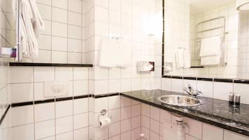 A modern bathroom with white tiles, a black countertop, a sink, and a mirror.