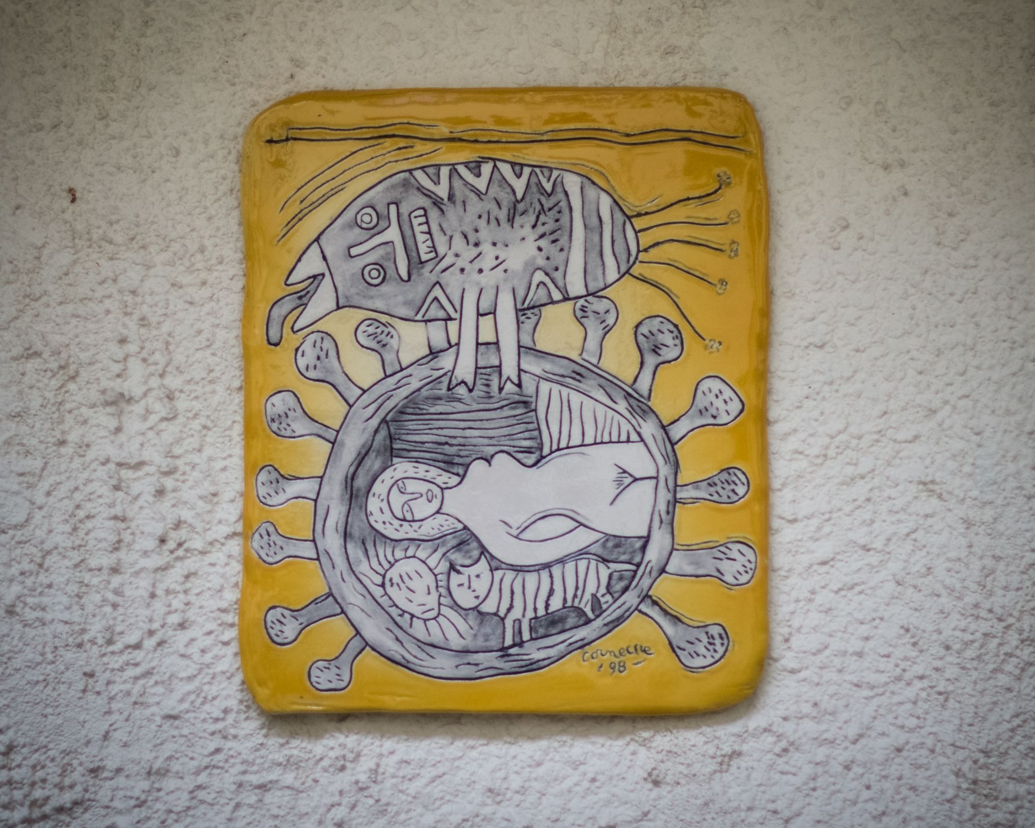 Een handbeschilderd kunstwerk met een gestileerde weergave van een gezicht, met een zonnestraal en een slangachtige figuur in het midden, op een gele achtergrond.