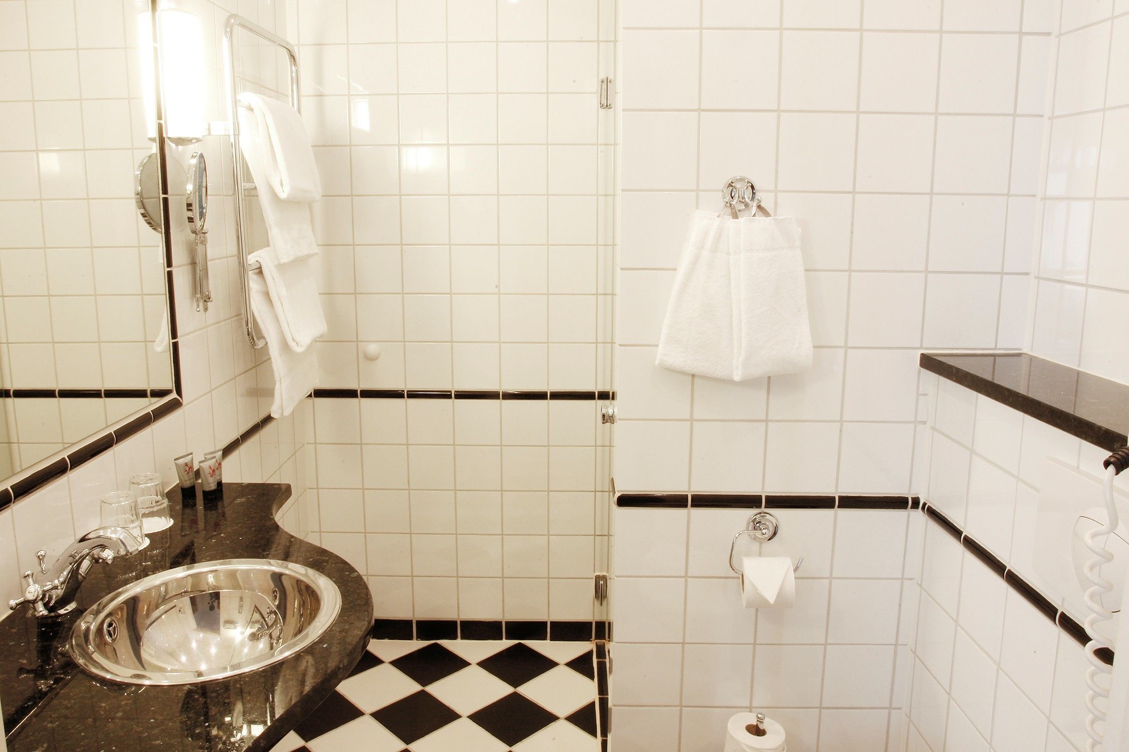 A bathroom with a sink, mirror, towel rack, and toilet paper holder.