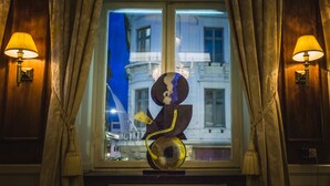 A room with a large window, two wall-mounted lamps, and a decorative glass sculpture. - Mayfair Hotel Tunneln (Malmö)