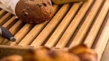 A wooden cutting board with two loaves of bread and a knife.