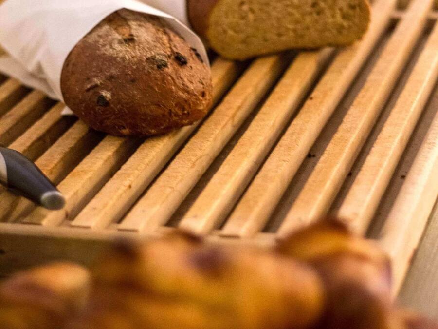 A wooden cutting board with two loaves of bread and a knife.