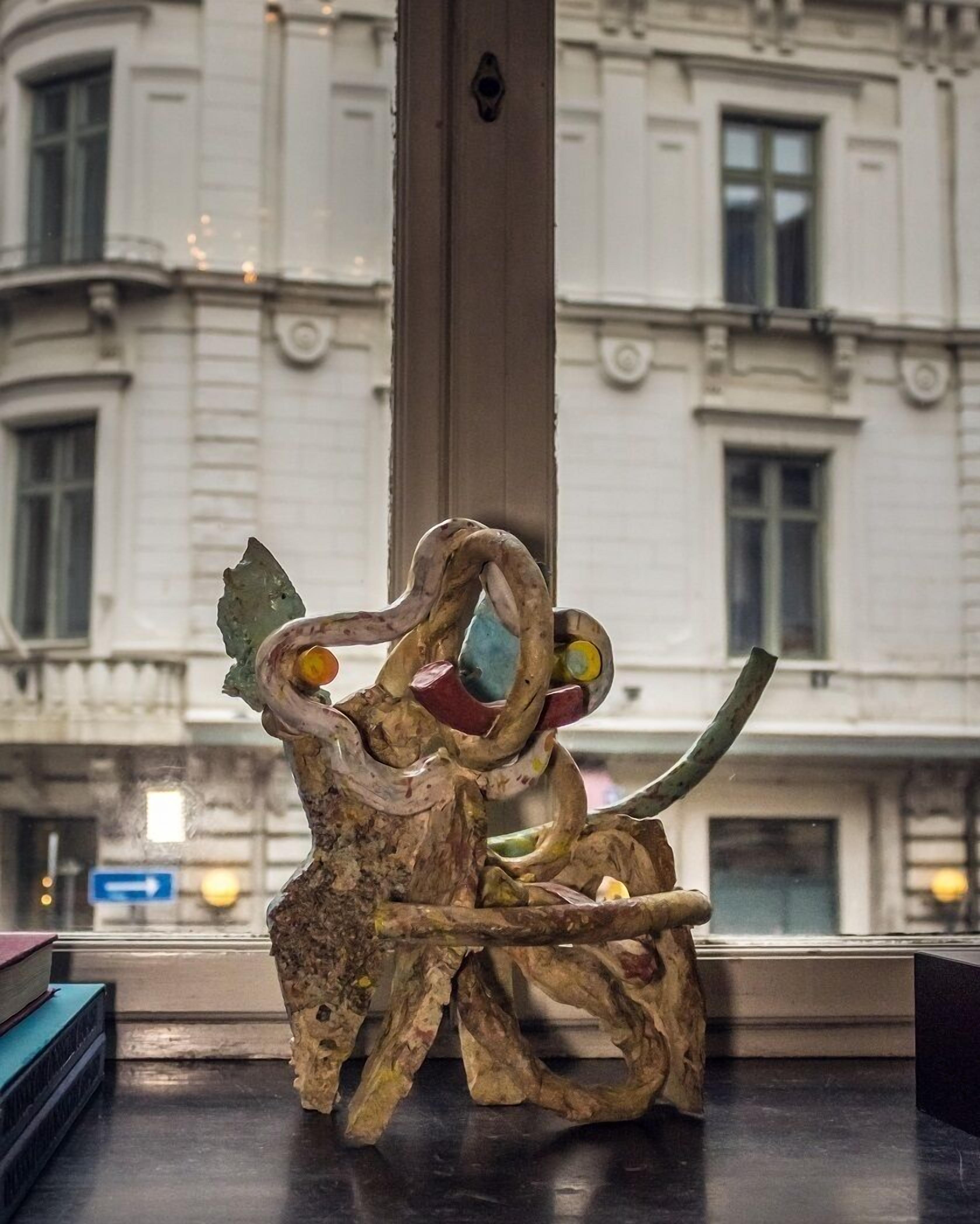 A sculpture of an elephant in a room with a window overlooking a building.