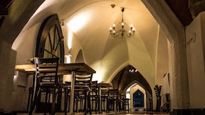 A dining area with a high arched ceiling, a chandelier, and multiple wooden chairs and tables. - Mayfair Hotel Tunneln (Malmö)