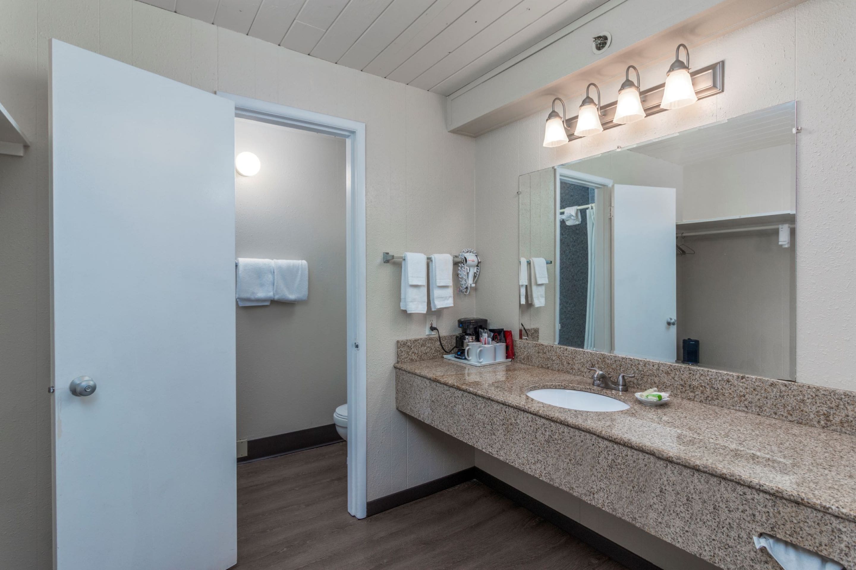 Une salle de bain avec un comptoir en granit, un lavabo, un miroir et un porte-serviettes.