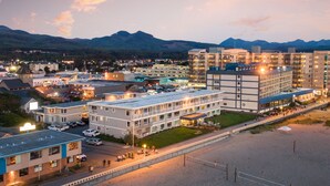 A hotel with multiple floors, a parking lot, and a beach area. - Seashore Inn on the Beach (Seaside)