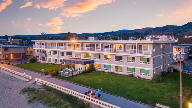 A multi-story hotel with a rooftop terrace and a pool area. - Seashore Inn on the Beach (Seaside)