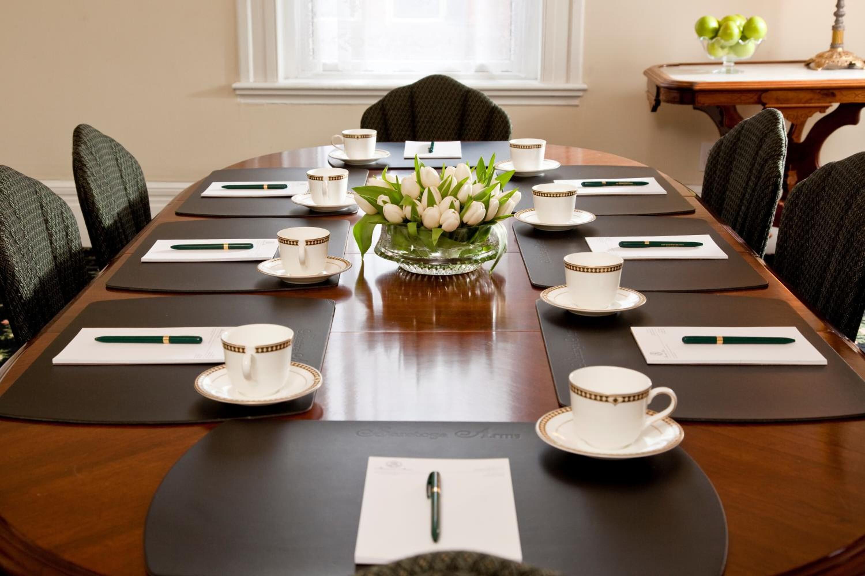 A conference room with a long table, chairs, and a vase of white tulips.